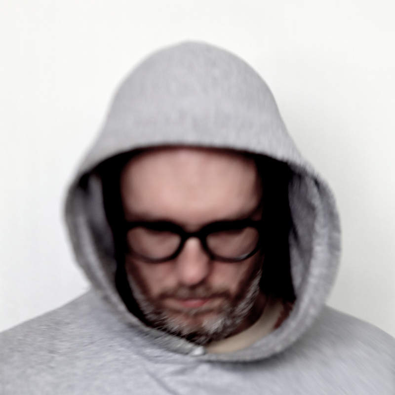 a blurry portrait of myself, in a grey hoodie, looking down